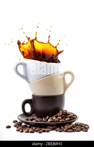 isolato da fondo bianco, un piattino con tre tazze di caffè di colore diverso da cui si genera uno spruzzo di caffè nero. Foto Stock