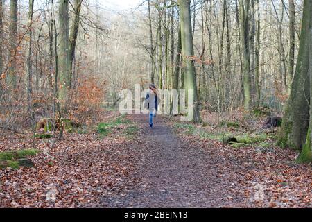 Una ragazza corre su un sentiero nel bosco Foto Stock