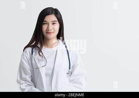 Attraente medico asiatico femminile guardando macchina fotografica con il viso sorridente, isolato su sfondo bianco con spazio copia. studio girato Foto Stock