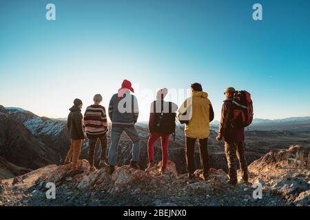 Un gruppo di escursionisti si trova in cima alla montagna e guarda il tramonto Foto Stock
