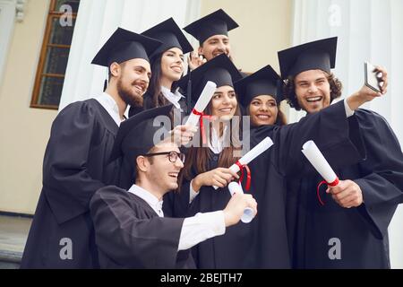 Gli studenti laureati vengono fotografati al telefono presso il college universitario. Foto Stock