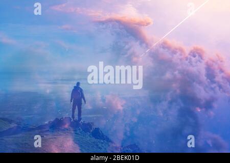 Escursionista con zaino in piedi in cima a una collina guardando una bella alba. Con una doppia esposizione e astratta, sogno sperimentale come edit. Foto Stock