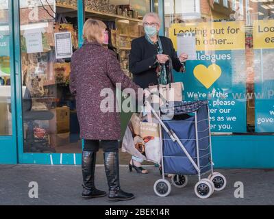Redhill, Surrey, Regno Unito - 10 aprile 2020 - una donna in maschere protettive andare a fare shopping durante lo scoppio del coronovirus Foto Stock