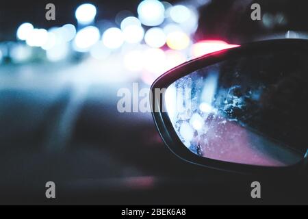 Luci notturne bokeh e specchietto retrovisore ad ala di auto Foto Stock
