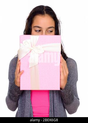 Studio di giovane bella ragazza adolescente nascosto dietro scatola regalo isolato contro sfondo bianco Foto Stock