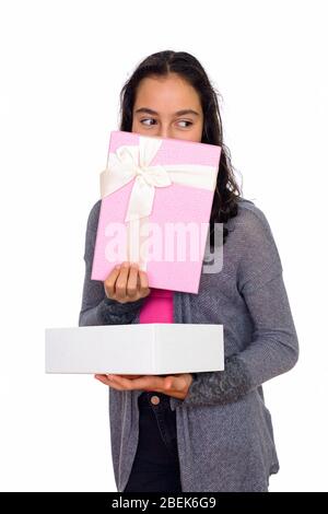 Studio di giovane bella ragazza adolescente nascosto dietro scatola regalo isolato contro sfondo bianco Foto Stock