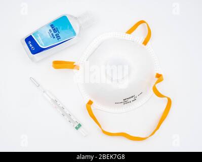 Attrezzatura utilizzata per la prevenzione del coronavirus COVID-19 SARS-cov-2 - maschera facciale per respiratore FFP2 N95, termometro e gel igienizzante per mani a base di alcol Foto Stock