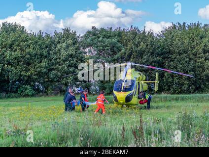 Pocklington, East Yorkshire, UK, 08/26/2015 - le mediche trasportano una persona injjuned su una barella all'ambulanza dell'aria di attesa. Foto Stock