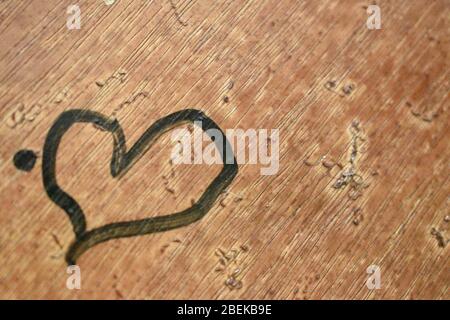 Vista primo piano della forma del cuore disegnata da un bambino con vernice nera in marrone di sfondo door.Day fotografia con fotocamera Nikon il 2020 aprile Foto Stock