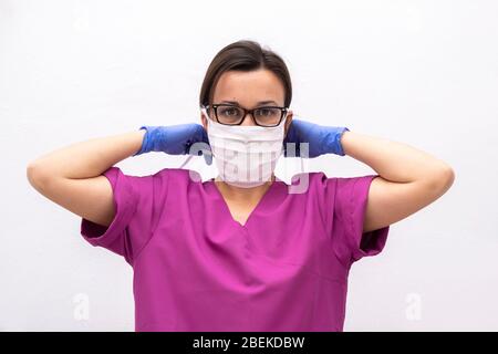 Femmina attraente medico o infermiere mettendo sulla maschera facciale protettiva. Foto Stock