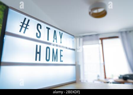 Coronavirus home segno lightbox con testo hashtag STAYHOME che si illumina in luce. Banner COVID-19 per promuovere l'isolamento auto rimanendo a casa. Appartamento sul retro Foto Stock