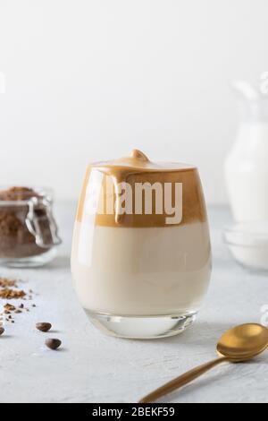 Bevanda coreana caffè Dalgona in vetro. Latte freddo con schiuma di caffè istantaneo su fondo bianco. Inquadratura verticale. Foto Stock