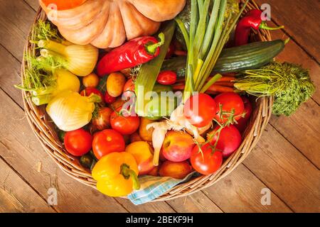 Cestino con verdure fresche biologiche su un pavimento in legno Foto Stock