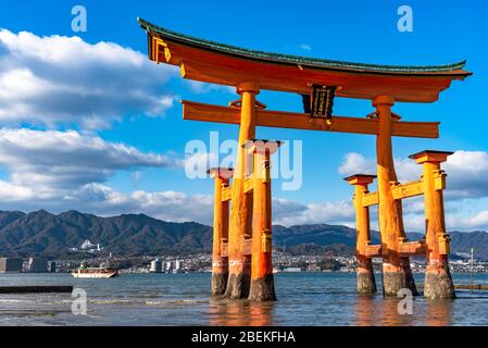 Il gigante rosso arancione galleggiante Grand o-Torii porta si trova nella baia di Miyajima spiaggia a bassa marea di fronte al santuario di Itsukushima in giornata di sole. Hiroshima Foto Stock