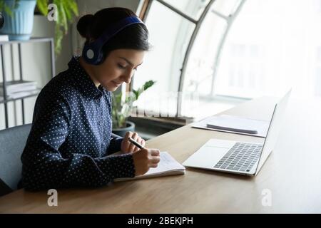 Le donne dipendenti in auricolari hanno una conferenza web con colleghi Foto Stock