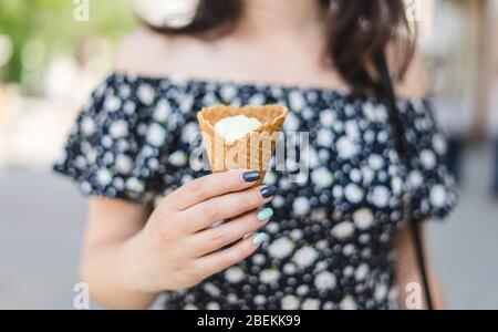 Donna joung tiene gelato alla vaniglia nel cono. Gelato alla vaniglia in un cono di waffle Foto Stock