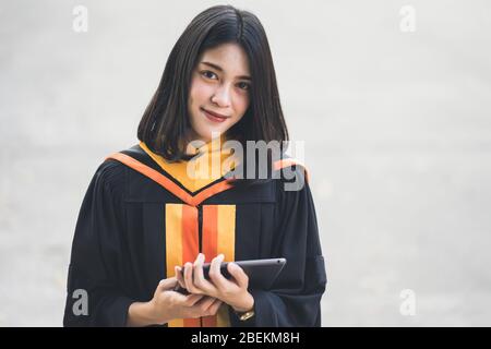 Giovani affascinanti laureate asiatiche celebrano la laurea dopo aver conseguito un diploma nel giorno di inizio. Foto Stock