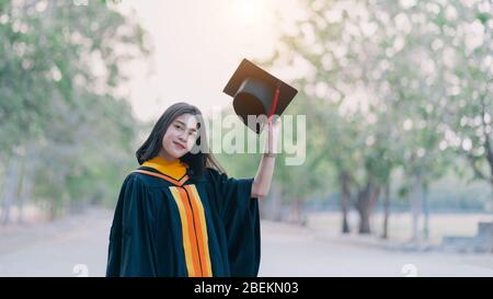 Giovani affascinanti laureate asiatiche celebrano la laurea dopo aver conseguito un diploma nel giorno di inizio. Foto Stock