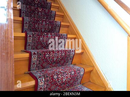 Scale con strisce di moquette a motivo rosso, vecchia scala in legno vintage, design antico Foto Stock