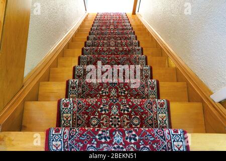 Scale con strisce di moquette a motivo rosso, vecchia scala in legno vintage, design antico Foto Stock