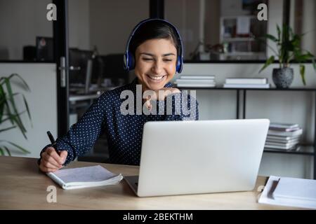 Sorridente donna in cuffia consultare il cliente online Foto Stock