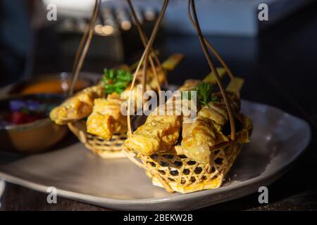 Spiedini di pollo al satay o al kebab su un piatto di ceramica nera con contorni di cetrioli, cipolle rosse, peperoni e salsa tailandese. Foto Stock