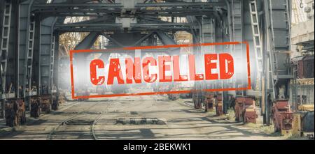 Iscrizione rossa "annullata" su uno sfondo sfocato di carri ferroviari e gru in produzione. Concetto: Crisi economica globale, riduzione degli scambi, Foto Stock