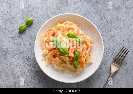 Fettuccine di pasta italiana con gamberi su tavola grigia. Vista dall'alto.
