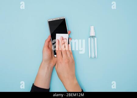 Donna pulizia e disinfezione del telefono cellulare per la prevenzione delle malattie da coronavirus Covid-19. Foto Stock
