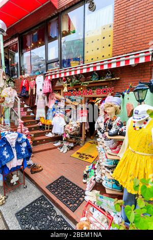 Tokyo, Harajuku, via Takeshita. Panama Boy usato negozio, esterno. Vari vestiti e scarpe fuori negozio su scaffali e appeso a parete. Foto Stock