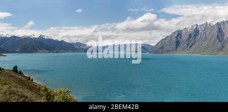 Paesaggio del lago alpino Hawea parte settentrionale con montagne innevate, girato in luce brillante primavera dalla costa occidentale vicino al Neck, Otago, South Islan Foto Stock