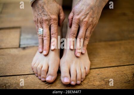 Primo piano delle mani e dei piedi di una donna matura Foto Stock