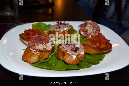 Primo piano di bruschette in stile italiano, varie carni e verdure miste su fette di pane tostate, cibo sano per il brunch o il pranzo, cucina rec Foto Stock