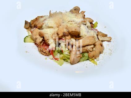 Primo piano di insalata biologica sana su piatto bianco, preparata con ingredienti freschi come verdure e crostini e ricoperta con parmigiano grattugiato Foto Stock