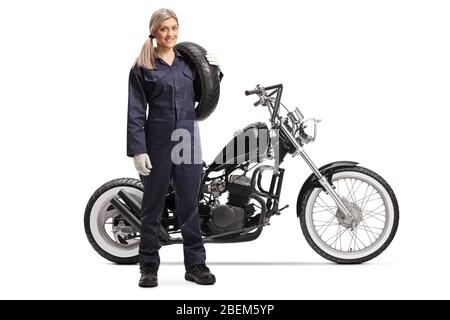 Ritratto a tutta lunghezza di una motocicletta femminile con una moto personalizzata che tiene un pneumatico isolato su sfondo bianco Foto Stock