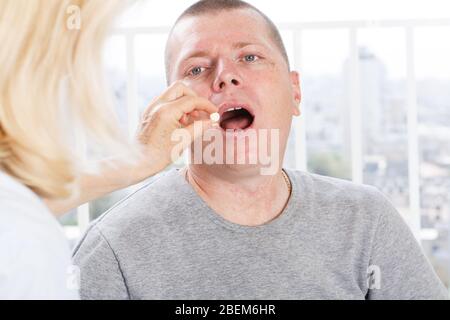 Mano di infermiere che dà il farmaco al paziente Foto Stock