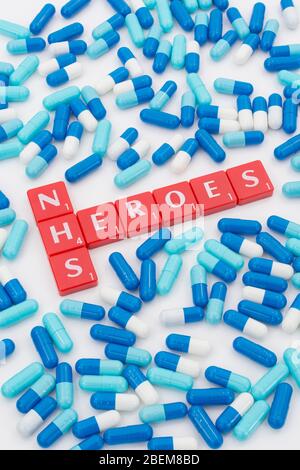 Piastrelle di lettere di eroi NHS & pillole blu assortite. Per NHS in Covid 19 pandemic, personale di NHS, prescrizioni di NHS, servizio nazionale britannico di salute, medicina in Regno Unito Foto Stock