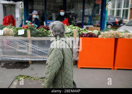 Bucarest, Romania - 14 aprile 2020: Donna anziana cammina da un mercato vegetale di strada durante il blocco del covid-19. Foto Stock