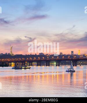 Vista della Madre Patria monumento sopra Dnipro river con Paton bridge e città di Kiev al tramonto, Ucraina Foto Stock