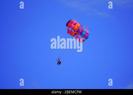 Persone in su nel cielo blu, parasailing Foto Stock