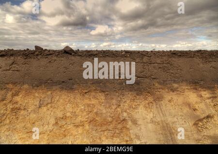 Il lato di un fossato di drenaggio di campo fresco scavato che mostra stratificazione di suolo topsoil umico e precipitazione di ferro in sottosuolo Foto Stock