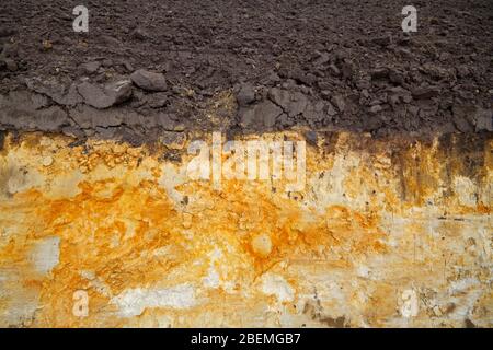 Il lato di un fossato di drenaggio di campo fresco scavato che mostra stratificazione di suolo topsoil umico e precipitazione di ferro in sottosuolo Foto Stock