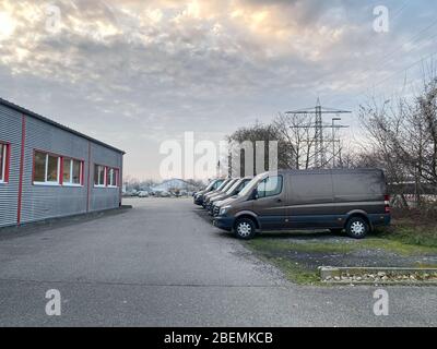 Fila di furgoni marroni per la consegna dei trasporti parcheggiati di fronte all'edificio del magazzino con un cielo spettacolare sullo sfondo - logistica moderna per il settore dell'e-commerce Foto Stock