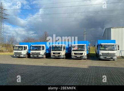 Berlino, Germania - 18 gennaio 2020: Più camion Mercedes-Benz Atego accanto a camion Man parcheggiati di fronte al magazzino con cielo spettacolare sullo sfondo Foto Stock