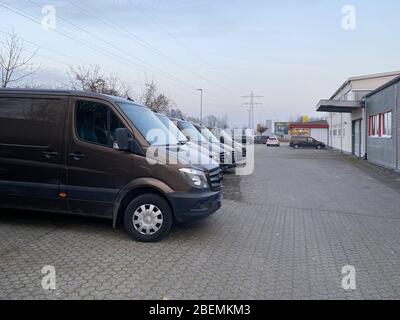 Vista laterale dei furgoni marroni per la consegna dei trasporti parcheggiati di fronte all'edificio del magazzino con una spettacolare logistica Sky moderna per il settore dell'e-commerce Foto Stock