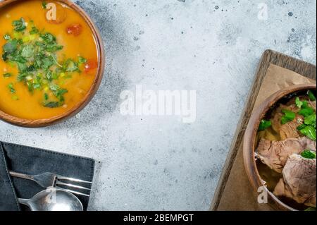 Zuppa tradizionale vietnamita Pho bo e zuppa tailandese piccante tom yum. Sfondo grigio con cibo asiatico, spazio per la copia Foto Stock