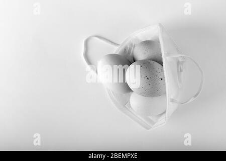 Concetto di Pasqua. Uova in maschera protettiva. Coronavirus, quarantena, foto in bianco e nero Foto Stock