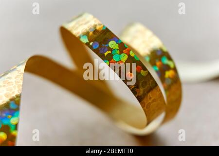 Nastro riccio dorato su sfondo di carta marrone kraft. Serpentina con ricci da utilizzare come sfondo natalizio, anniversario, matrimonio o celebrazione. Foto Stock