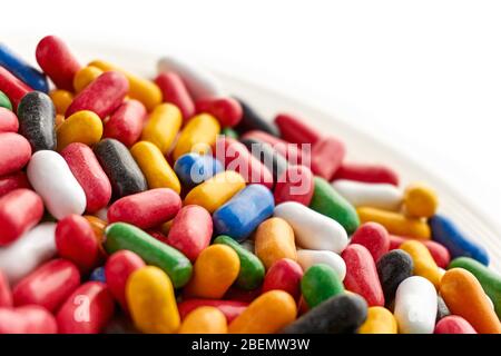 Primo piano di caramelle dolci colorate e lucide in blu, rosso, giallo, verde, nero e bianche su piattino. Angolo olandese con spazio di copia. Foto Stock