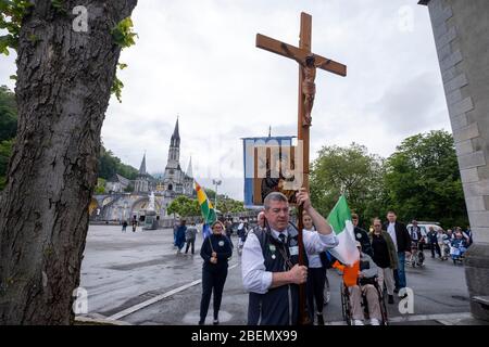 Eirrish pellegrini che portano una croce con uno scultore di Gesù Cristo camminando sui terreni del santuario di Lourdes, in Francia, Europa Foto Stock